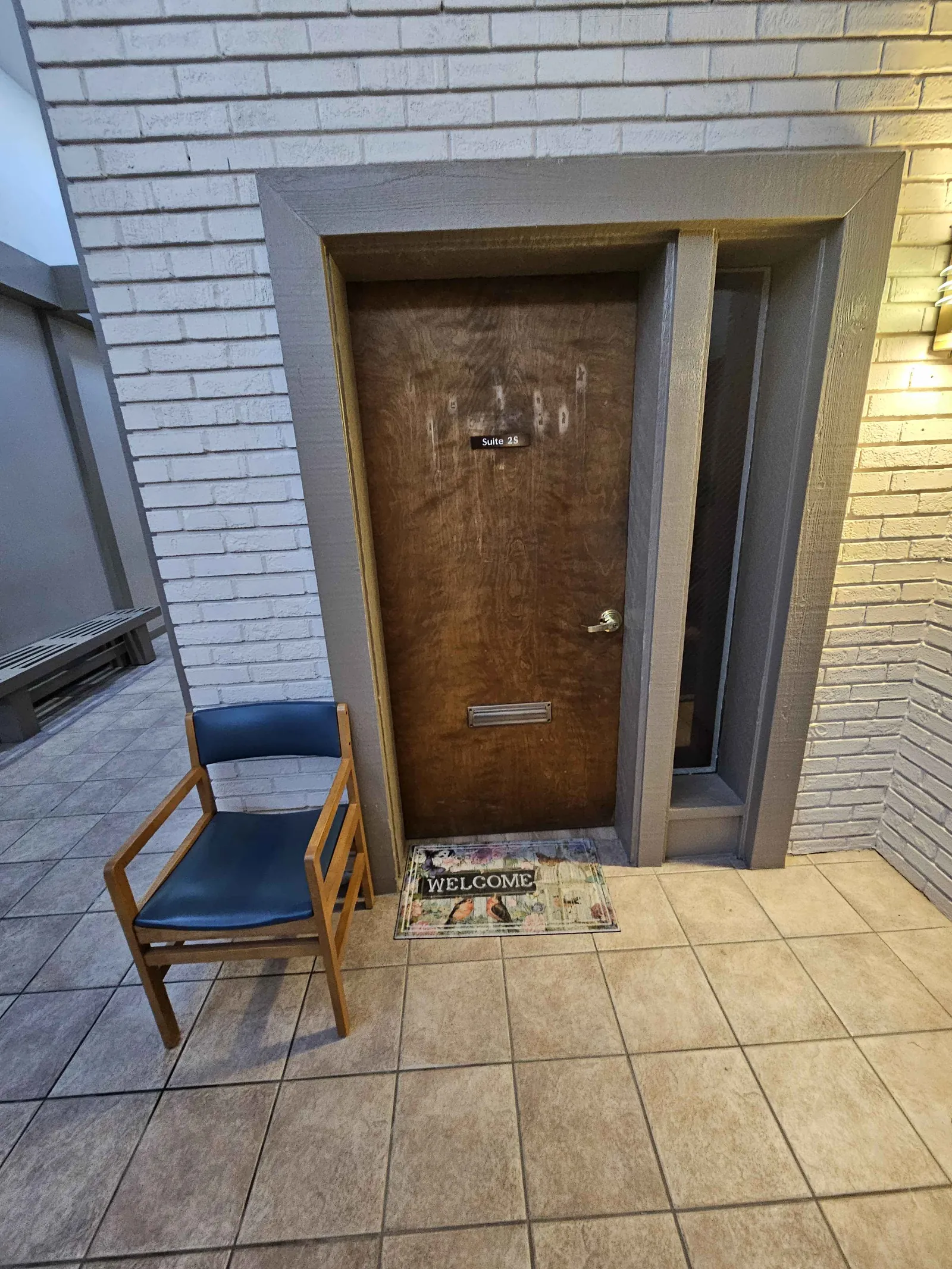 Private therapy suite entrance door with welcome mat at Enlitens Counseling — 10000 Watson Rd Crestwood MO
